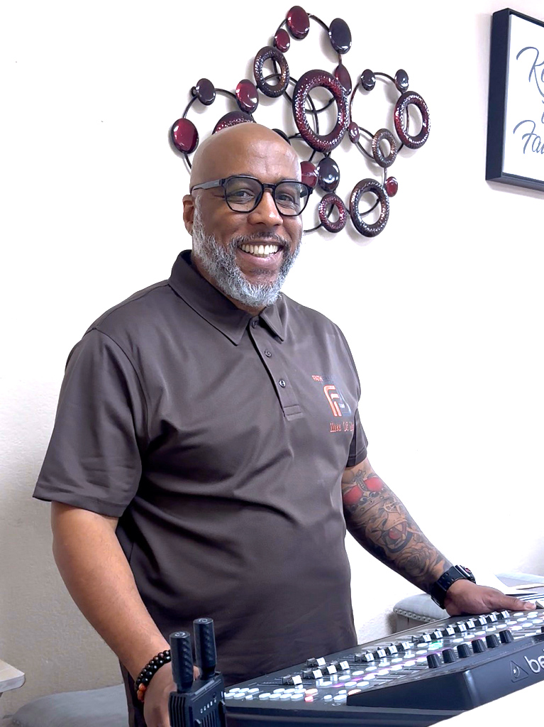 Smiling man in a Faith Fellowship polo at the soundboard